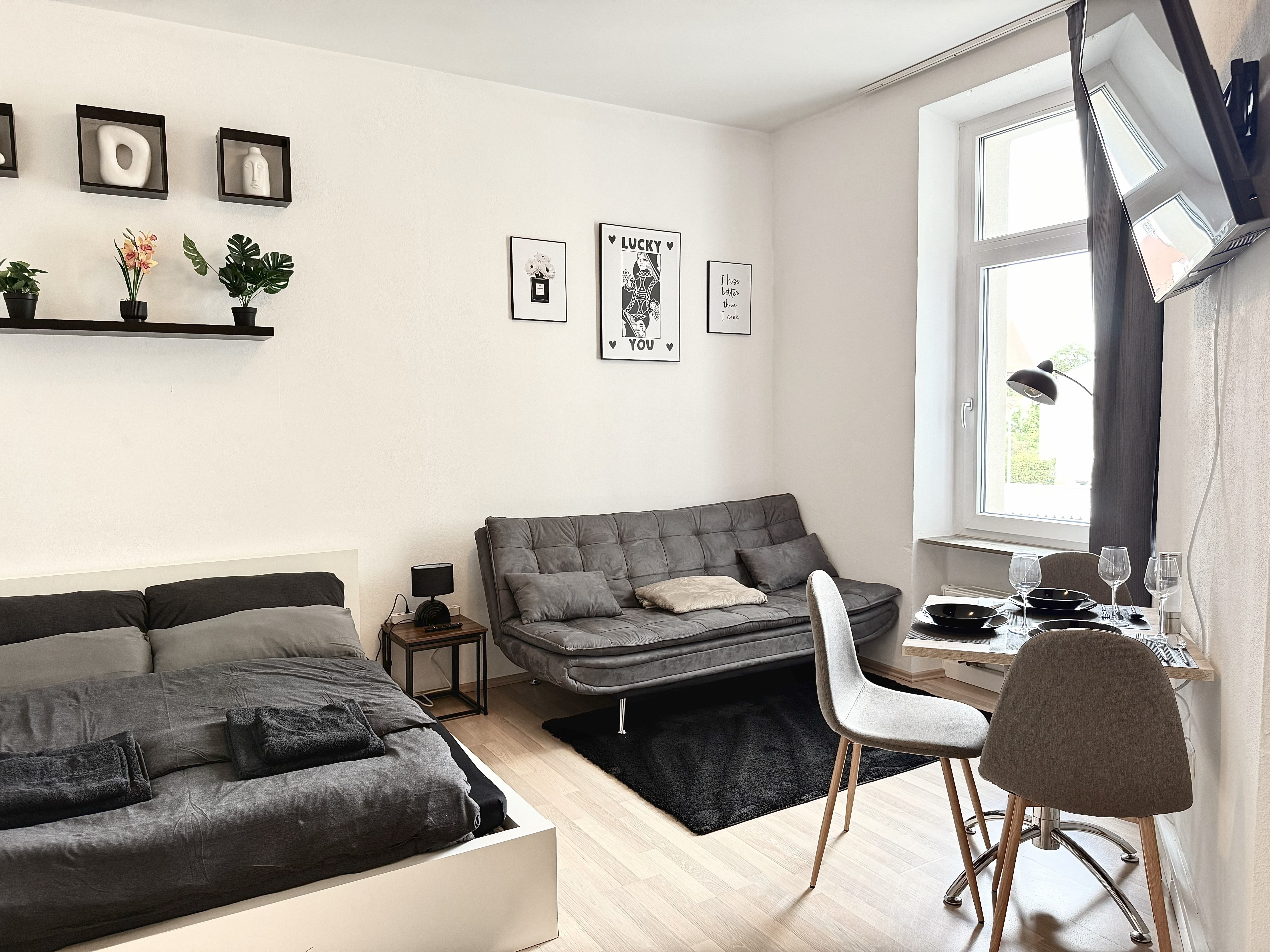 Wohnung 25 – Wohnbereich mit Doppelbett, Sofa und Esstisch